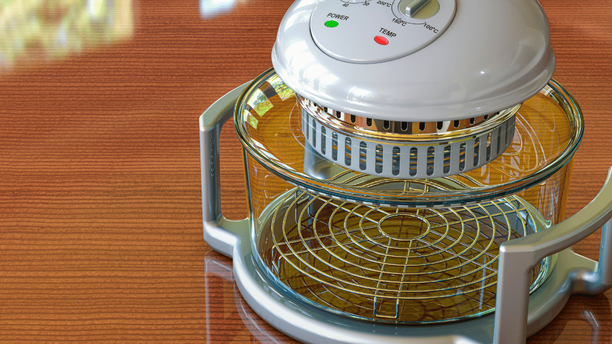 Close-up of a person using a food chopper to dice onions, with whole onions, a carrot, and a cutting board in the background on a kitchen counter.