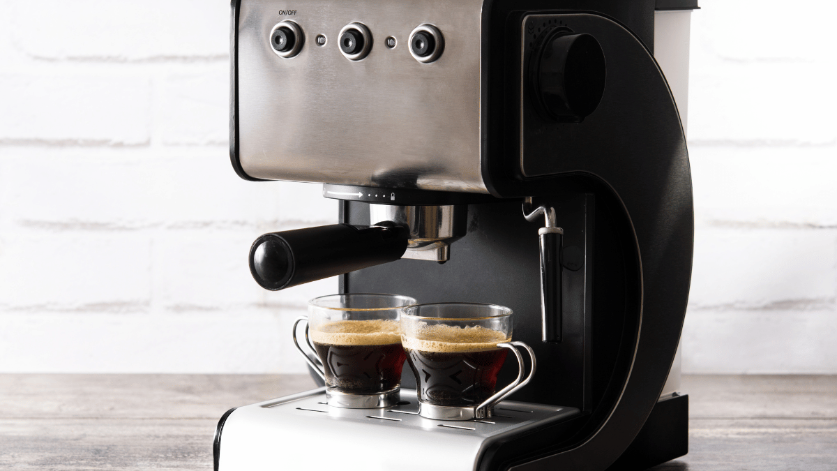 Modern espresso machine brewing two cups of coffee with rich crema, placed on a kitchen countertop with a white brick wall background.