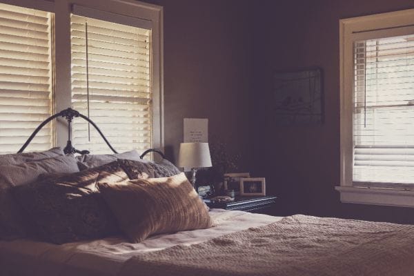 Sunlit UK bedroom with light coming through window blinds