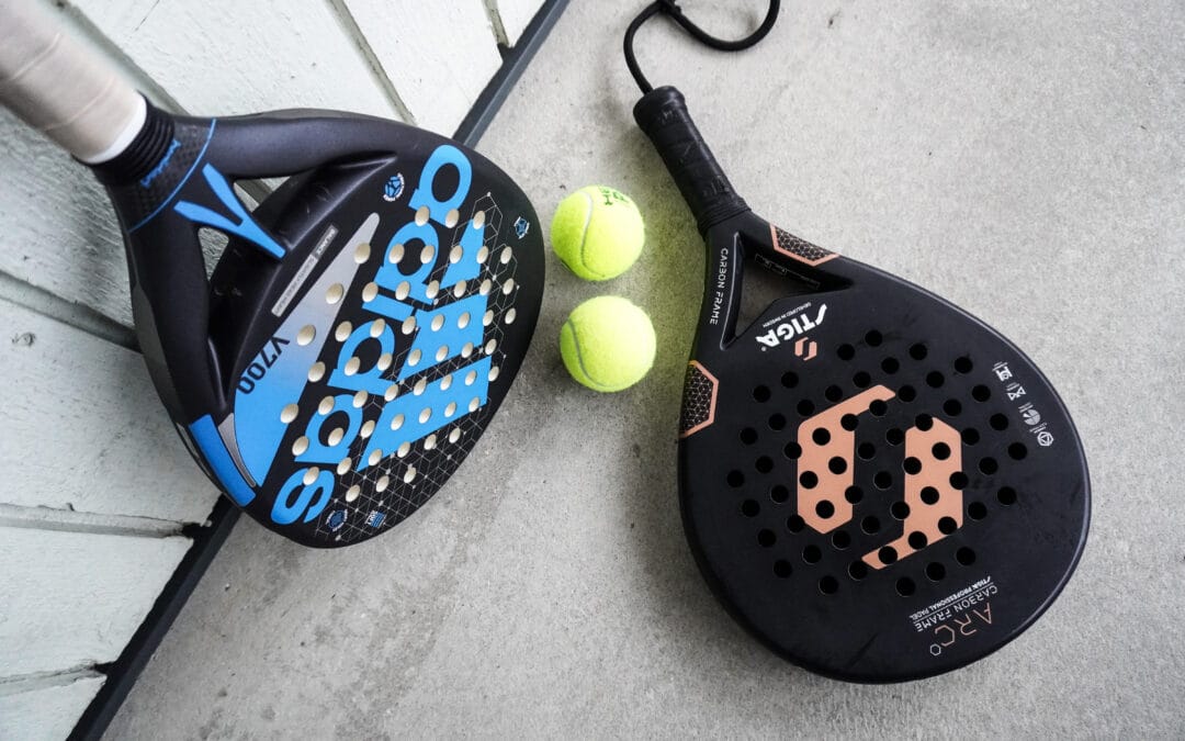 Two padel rackets and padel balls resting on a padel court