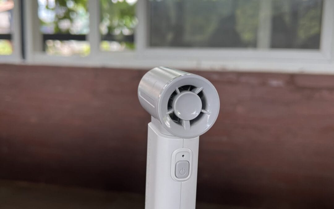 White portable handheld fan standing on a wooden table