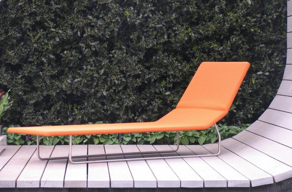 Orange zero gravity style sun lounger on a wooden deck in a garden