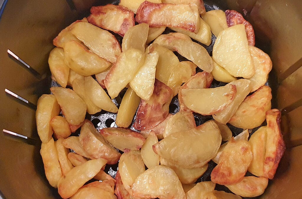 Golden roast potato wedges filling the basket of an air fryer