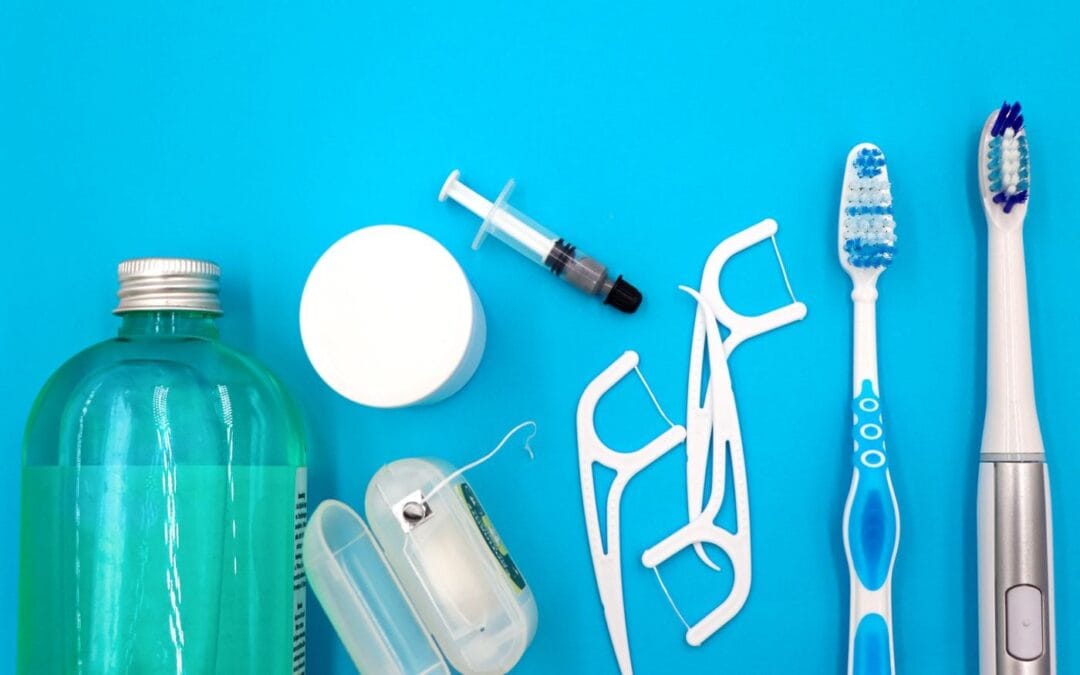 Toothbrushes, floss picks and mouthwash laid out on a blue background