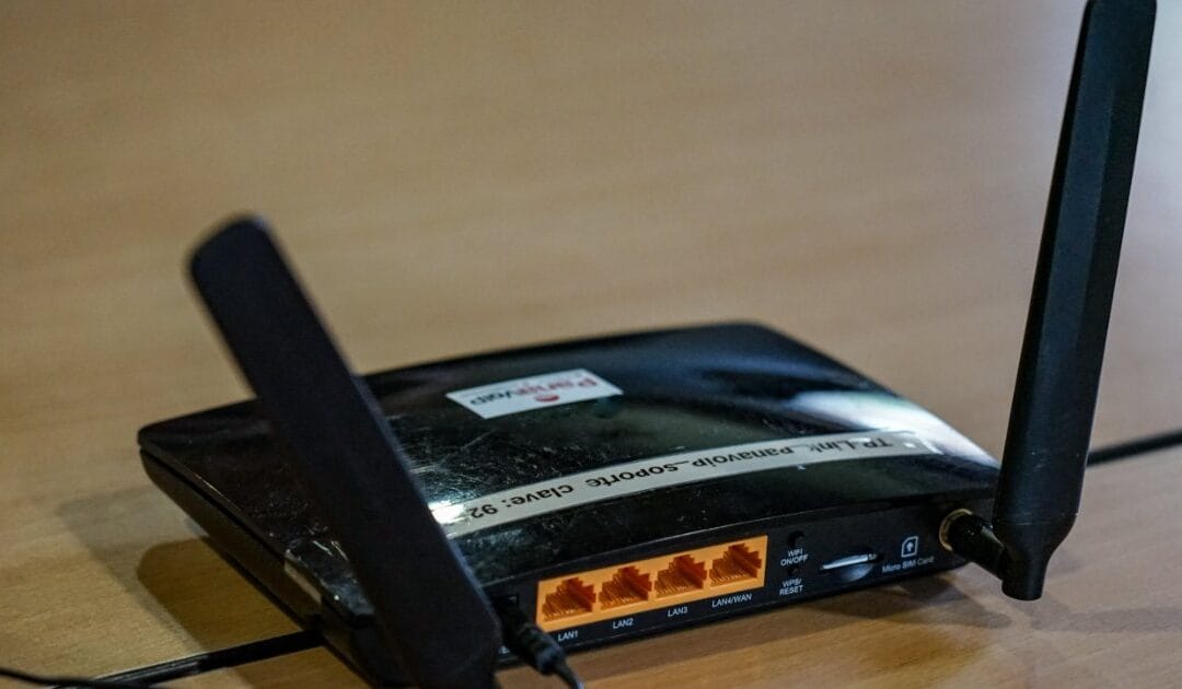 A black wireless router with two antennas on a wooden surface
