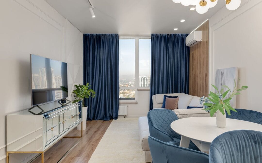 Living room with floor-length blue velvet curtains drawn beside a window