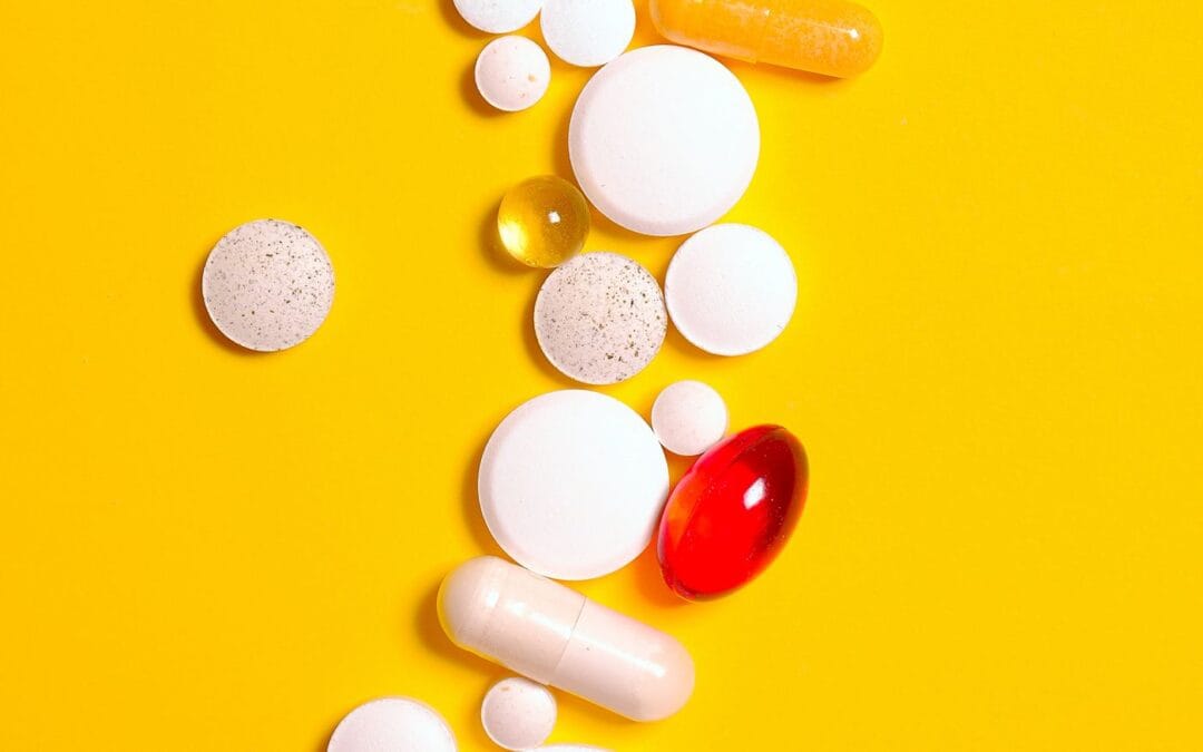 Assorted vitamin tablets and capsules on a yellow background