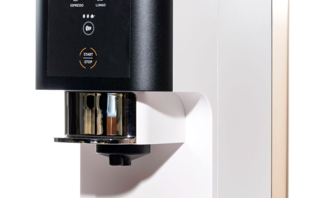 Close-up of a black coffee machine control panel with a Start/Stop button and a chrome portafilter below it.