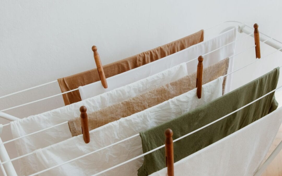 Laundry drying on a white indoor clothes airer held with wooden pegs