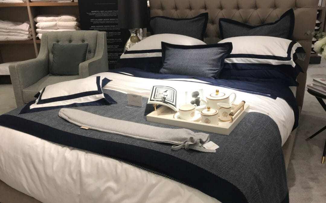 A long hot water bottle on a tray on a made bed