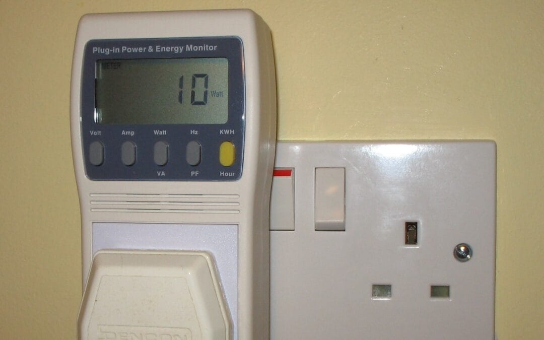 A plug-in power and energy monitor reading 10 watts, plugged in beside a UK mains socket