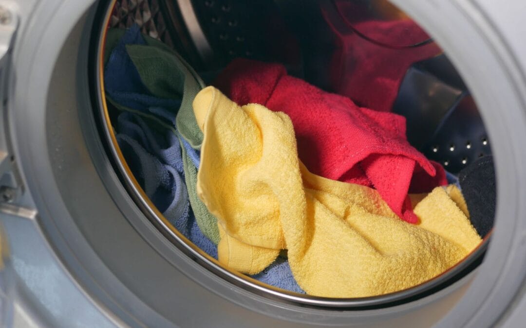 Close up of an open front loading washing machine drum with folded towels inside and the rubber door seal visible