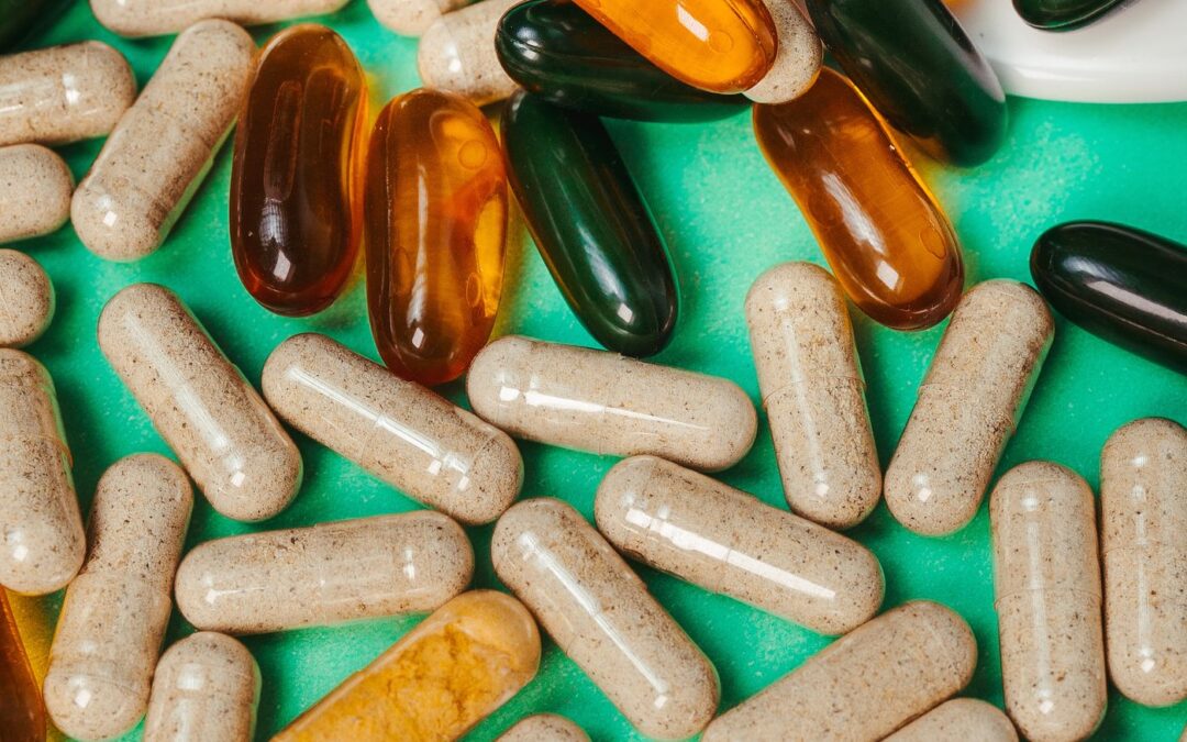 A close-up of assorted supplement capsules and tablets on a green background