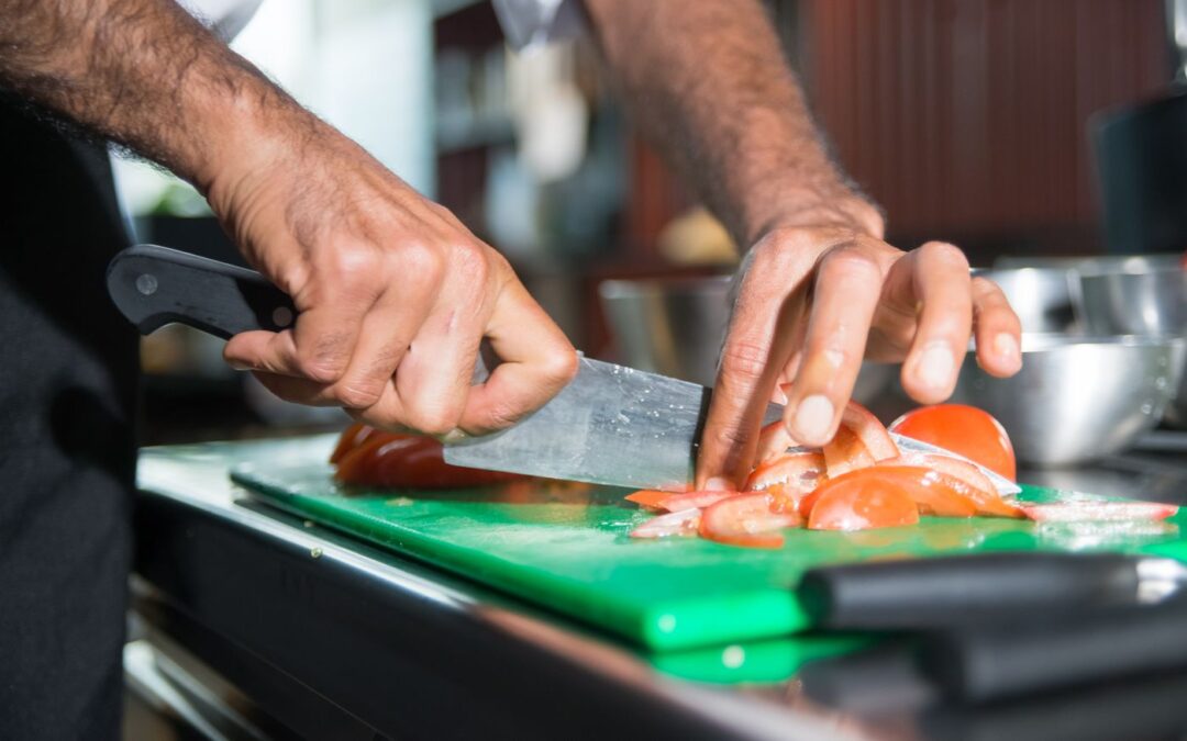 Chef slicing tomatoes with a kitchen knife