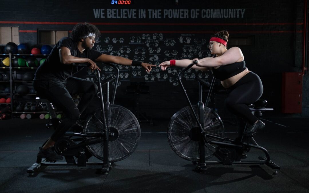 Two people on exercise bikes bumping fists mid-workout