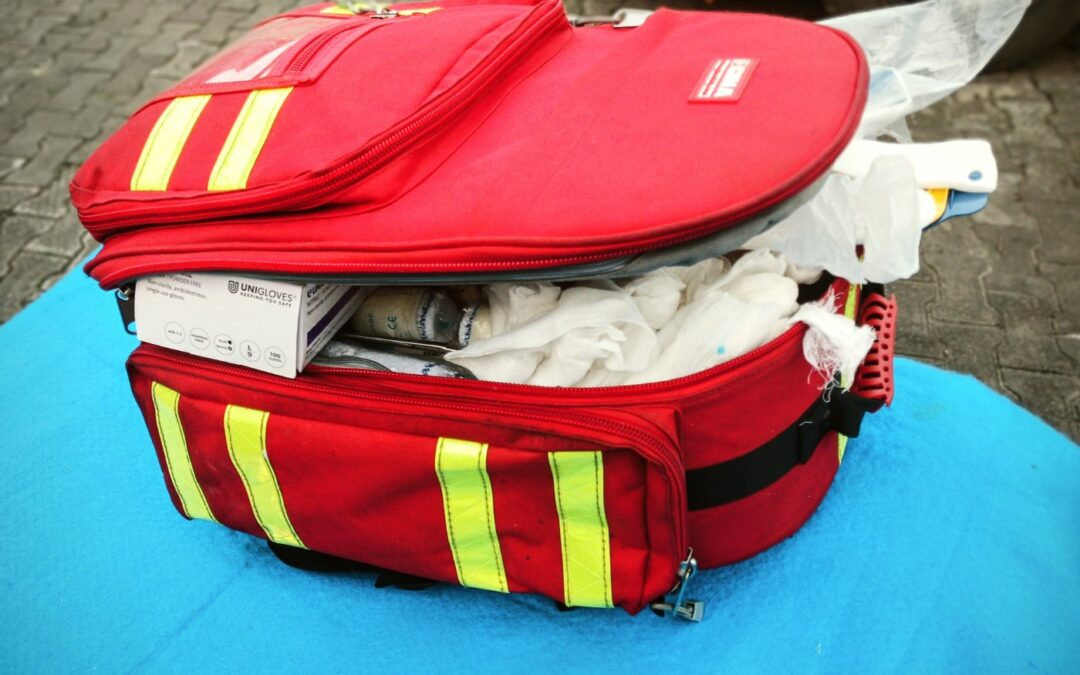 An open red first aid bag packed with sterile dressings and a box of disposable gloves