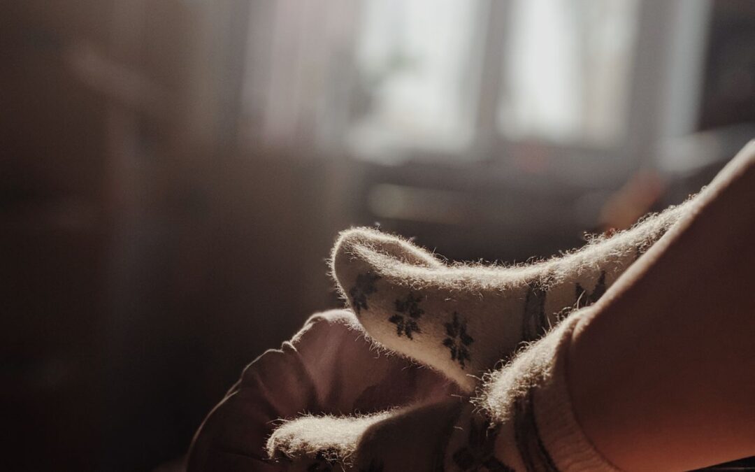 Feet in thick wool socks resting in warm window light