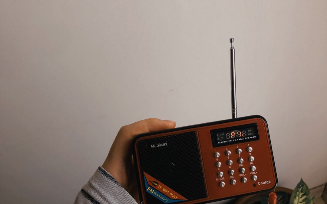 Hand holding a small portable FM radio with its aerial extended