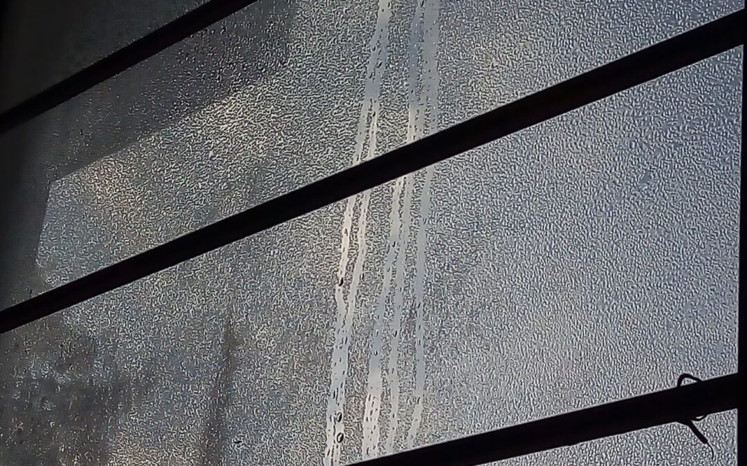 Heavy condensation running down the inside of a window pane on a cold morning