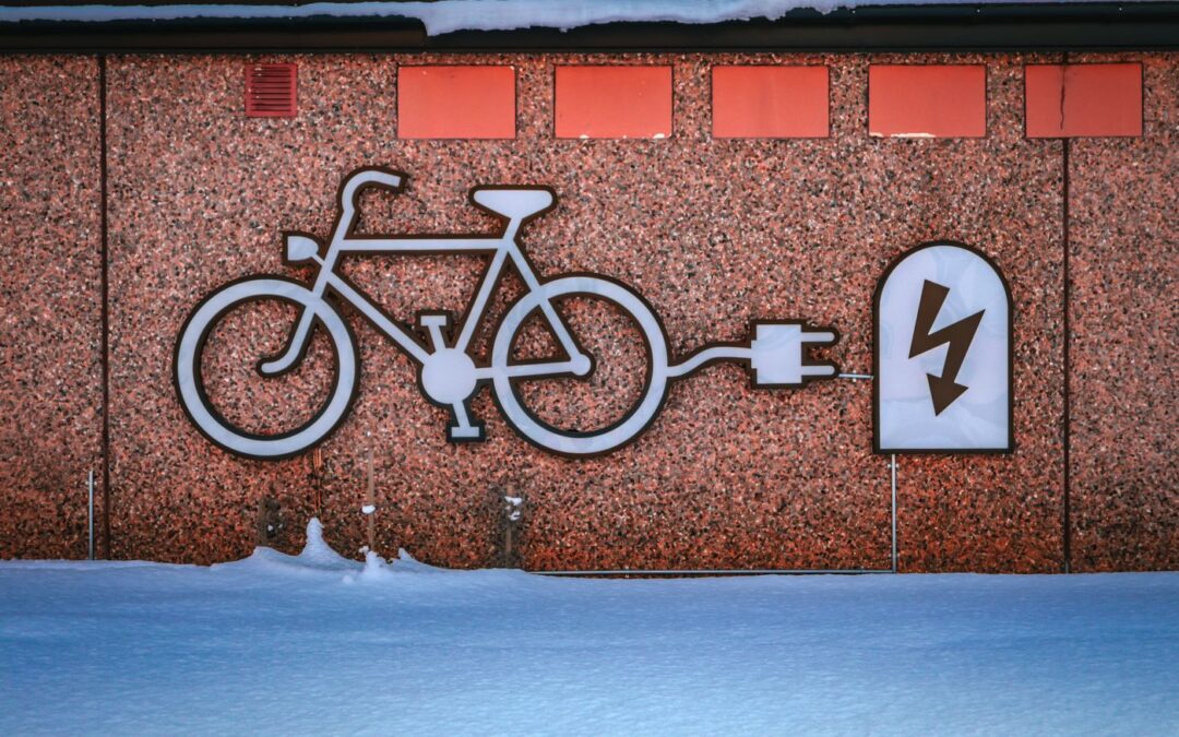 A wall sign showing a bicycle plugged into an electric socket, above snow