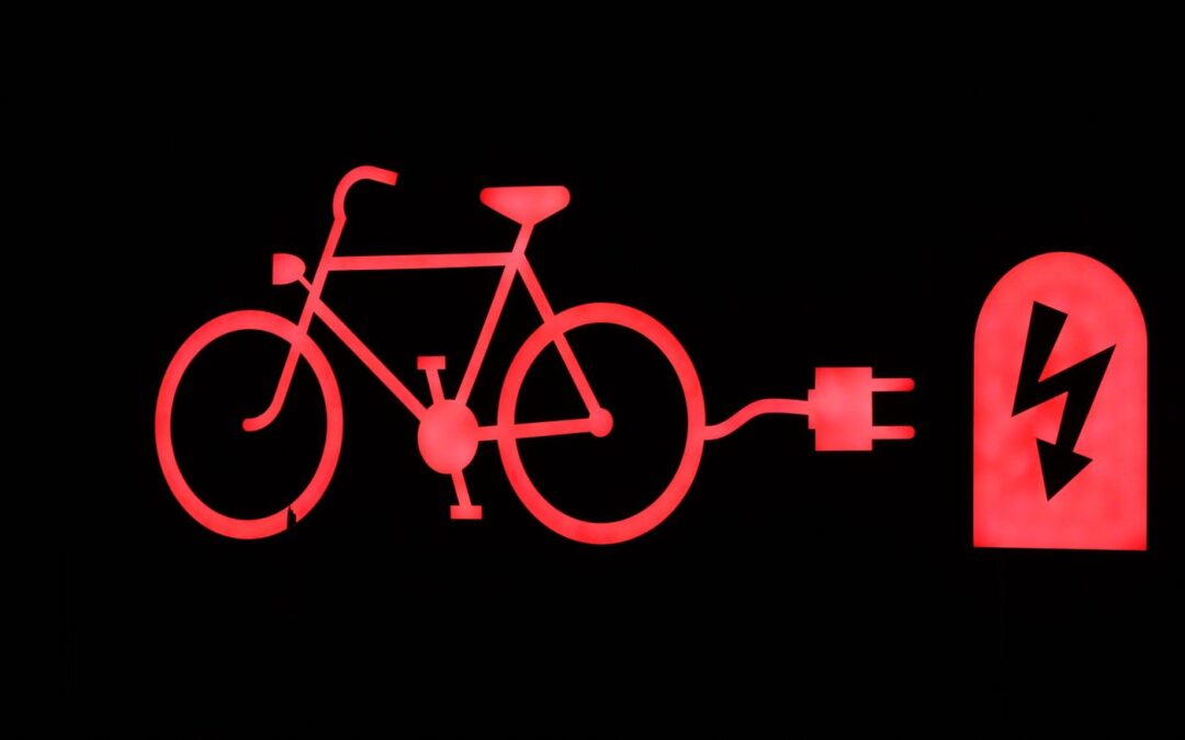 A red illuminated sign of a bicycle connected to a charging plug