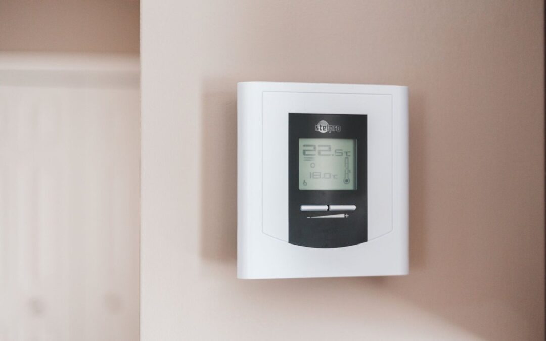 A digital thermostat with an LCD display mounted on a wall