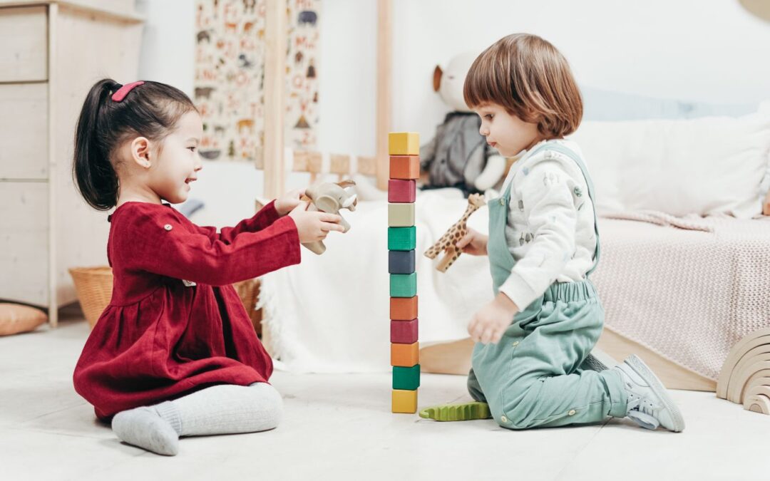 Two young children building a tower of wooden blocks