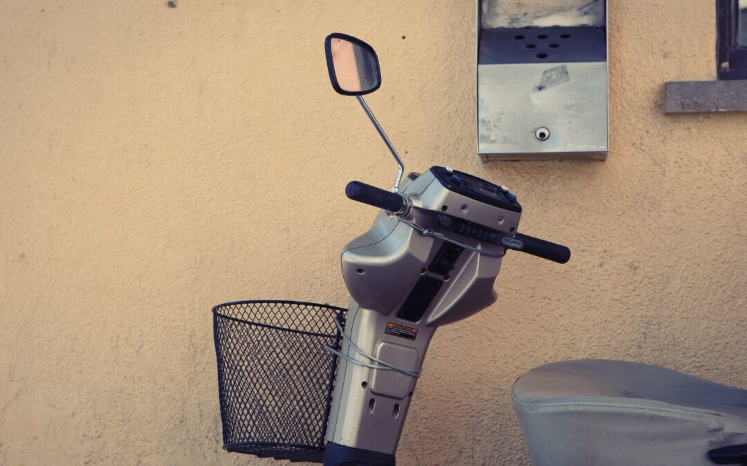 The tiller, basket and mirror of a mobility scooter parked indoors