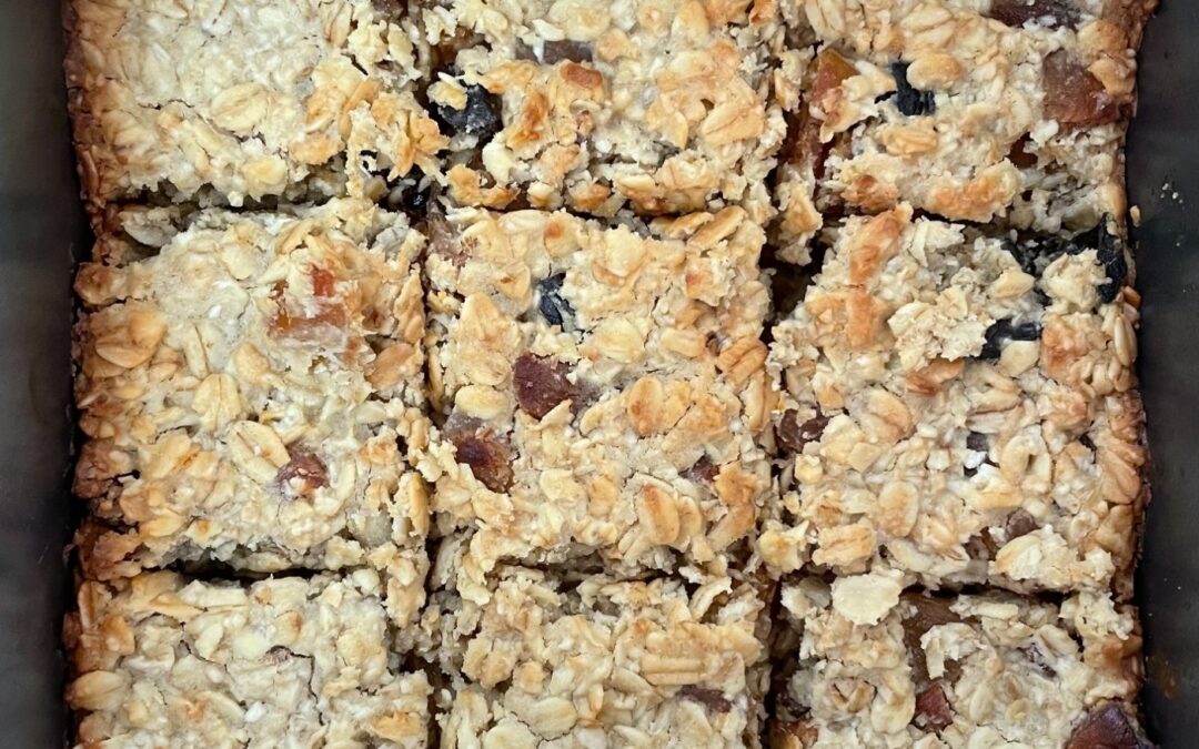 Oat flapjack cut into squares in a baking tin, photographed from above
