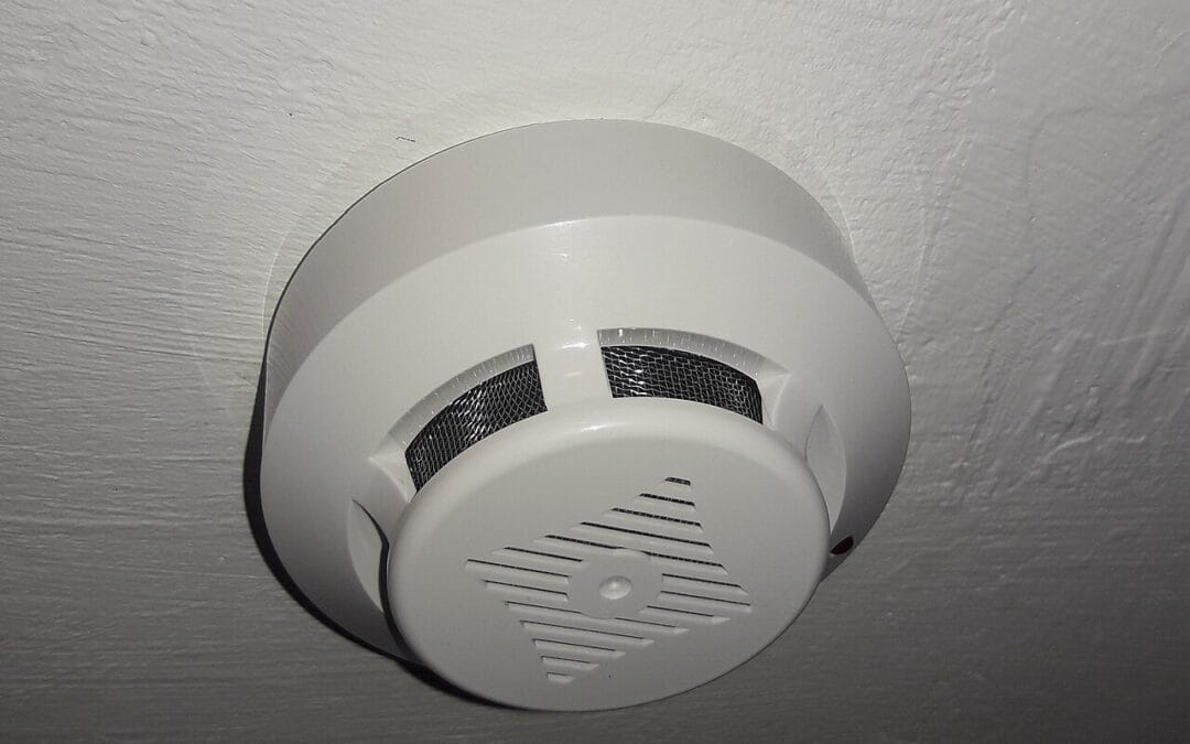 White optical smoke alarm mounted on a painted ceiling